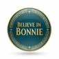 Pinback button badge with 'BELIEVE IN BONNIE' on dark teal, gold border and accents