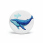 Round pinback button with blue whale illustration on a white background