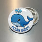 Whale pinback button with blue Ocean Buddy text and whale cartoon illustration