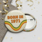 2.25-inch pinback button featuring “BORN IN 1971” text with rainbow wave design