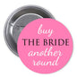 Pink pinback button: 'buy THE BRIDE another round' text on round face.