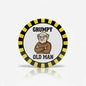 Round pinback button with striped border and “GRUMPY OLD MAN” graphic