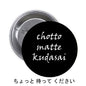 Black round pinback button with "Chotto matte kudasai" lettering