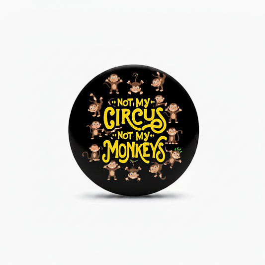 A round black button or badge featuring the text 'NOT MY CIRCUS NOT MY MONKEYS' in yellow, surrounded by small cartoon monkey illustrations, shown on a light gray background.