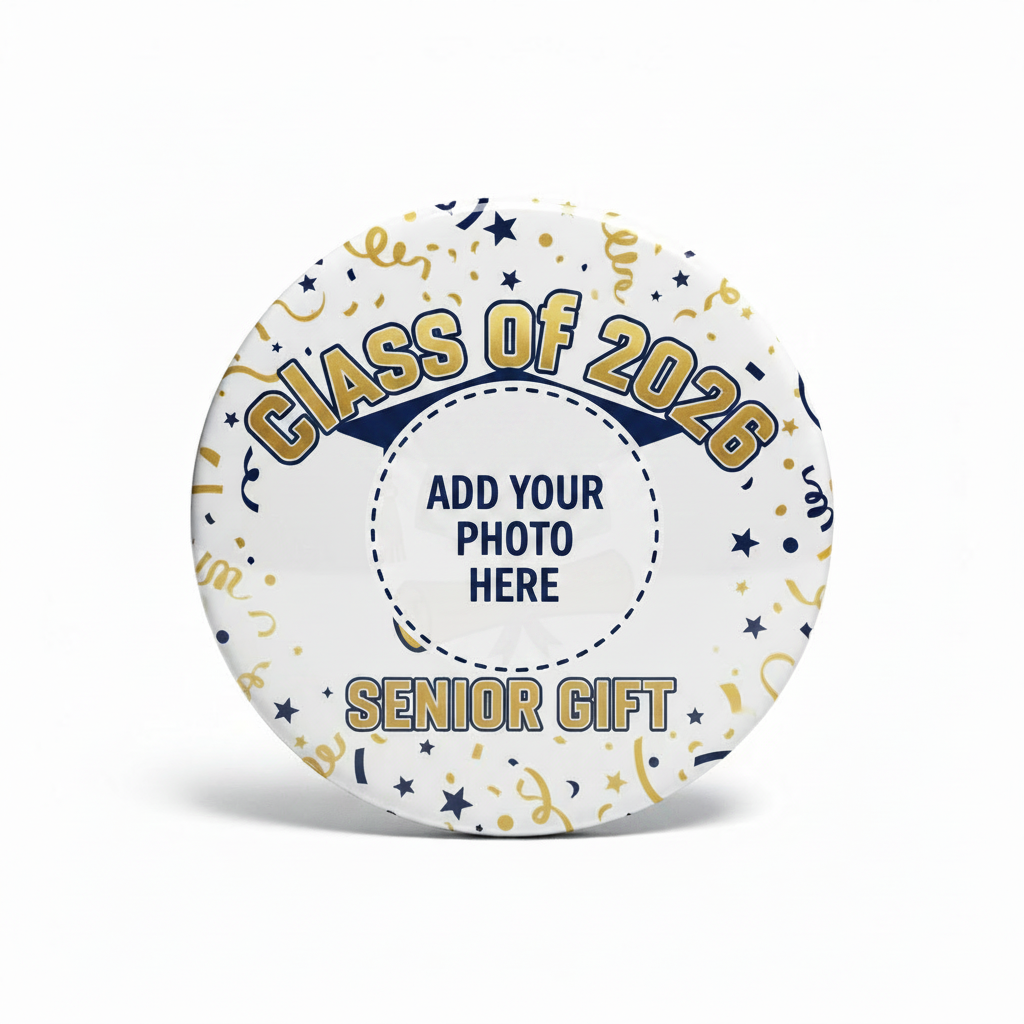 A round pinback button badge featuring a 'Class of 2026 Senior Gift' graduation design. The badge has a white background decorated with gold and navy blue confetti, streamers, and stars, with a navy blue and gold graduation cap and diploma illustration in the center.