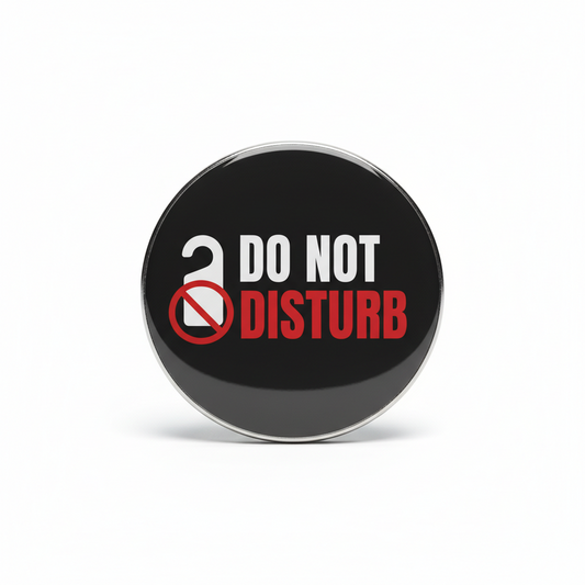 A round black pinback button with a silver metal rim, featuring the text 'DO NOT DISTURB' in white and red, alongside a white open lock icon with a red prohibition symbol, shown on a white background.
