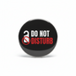 A round black pinback button with a silver metal rim, featuring the text 'DO NOT DISTURB' in white and red, alongside a white open lock icon with a red prohibition symbol, shown on a white background.