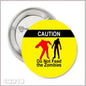 1.25-inch pinback button with yellow caution graphic and zombie warning text