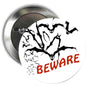 Round Halloween pinback button with black bats and red BEWARE text on white background
