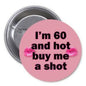 Round pink pinback button with black text: I'm 60 and hot, buy me a shot