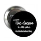 Round black pinback button with white quote text: "The dream is still alive"