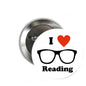 Round metal pinback button with black text, glasses, and red heart reading symbol