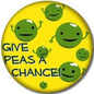Round yellow pinback button with green pea face icons and “GIVE PEAS A CHANCE!” text