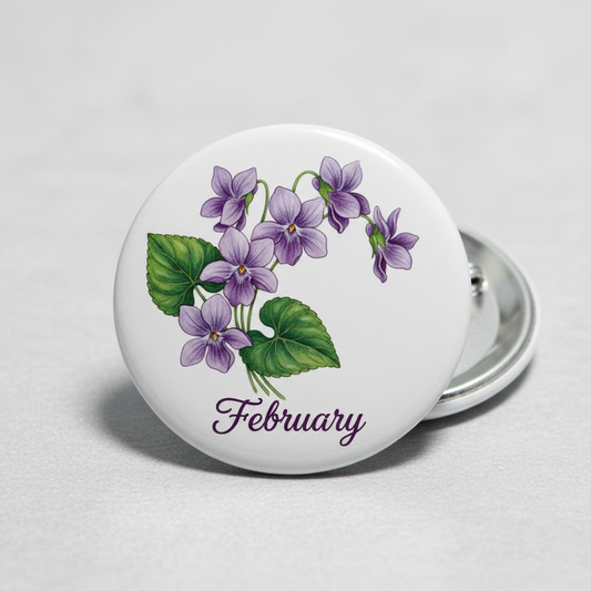 Round February flower pinback button, purple blossoms with green leaves, silver metal back