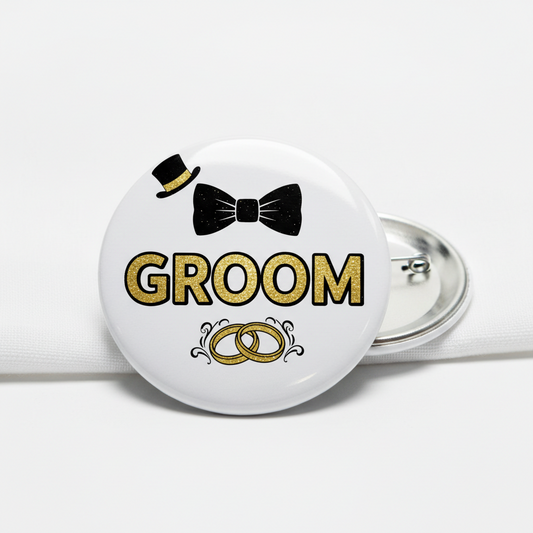 Groom pinback button with black bowtie, gold “GROOM”, wedding rings, silver pin backing
