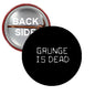 Round pinback button: black face with 'GRUNGE IS DEAD' and red rim