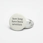 Round white pinback button with black text on front and silver back clasp