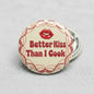 2.25-inch pinback button with red lips and “Better Kiss Than I Cook” text