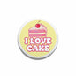 Round pinback button with yellow background, pink “I LOVE CAKE” text and cake with cherry.