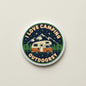2.25-inch camping-themed round pinback button with camper, mountains, trees, and text