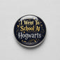 Round Hogwarts pinback badge, dark background with gold text 'I Went To School At Hogwarts'