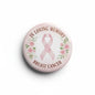 Round breast cancer remembrance pin with pink ribbon, flowers, and text "In Loving Memory"