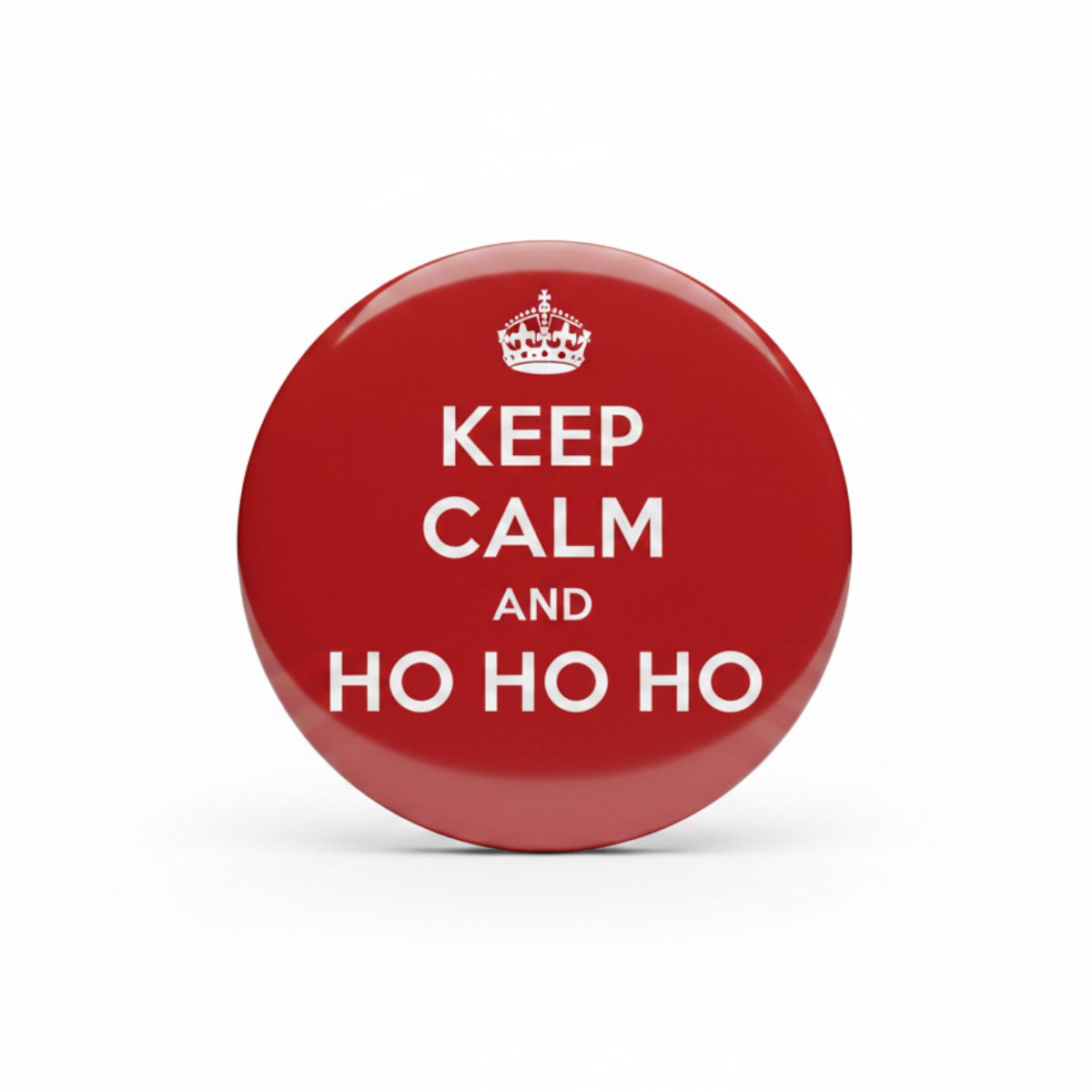 A round red button badge with a silver metal rim, featuring a white crown and the text 'KEEP CALM AND HO HO HO' in white, centered on a plain white background.