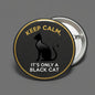 Round black pinback button with gold border, black cat silhouette and “Keep Calm” text.