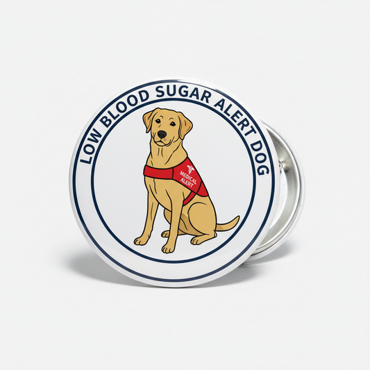 A round pin-back button featuring a cartoon Labrador retriever wearing a red 'Low Blood Sugar Alert Dog' vest, with the text 'LOW BLOOD SUGAR ALERT DOG' around the border, shown on a light gray background.