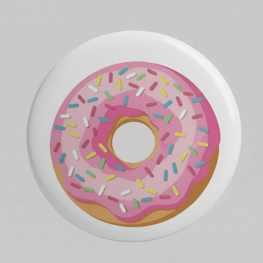 A round pin-back button badge featuring a pink frosted donut with colorful sprinkles and the words 'Birthday Party' in bold white letters with a purple outline, shown on a light gray background.