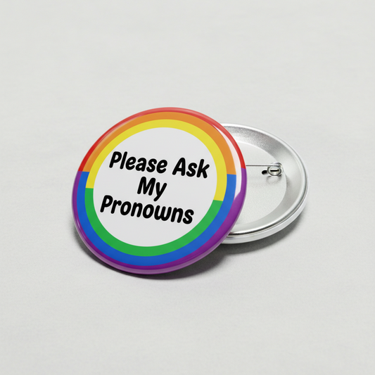 Rainbow circle pinback button with “Please Ask My Pronouns” text and metal back