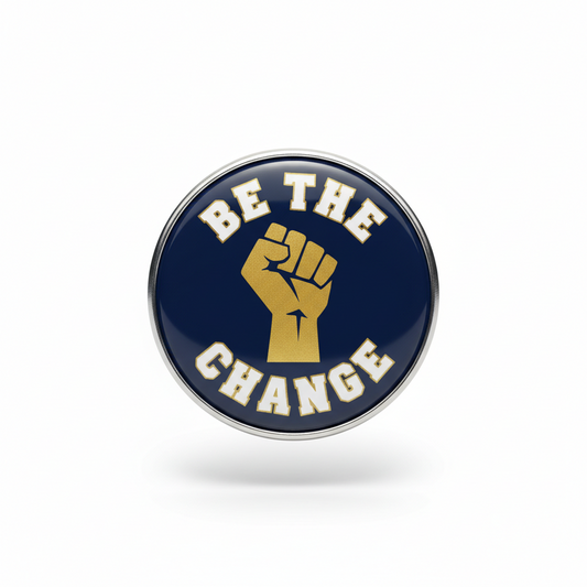Round enamel lapel pin with raised-fist icon and 'BE THE CHANGE' text