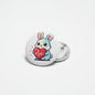 Rabbit pinback button with cartoon bunny holding a red heart, round white face, metal back