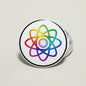 Round pinback button with colorful atom logo, silver rim, visible metal pin backing.