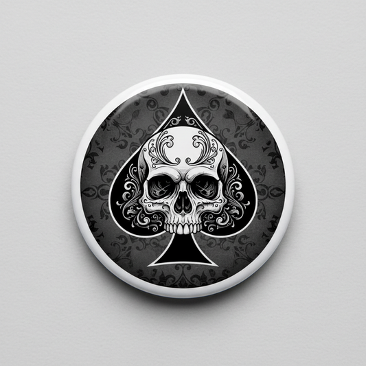 Skull and spade pinback badge with ornate black-and-white design, round silver rim