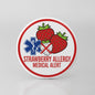 Round medical alert pin: red border, strawberry icon, STRAWBERRY ALLERGY text.