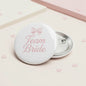 Round pinback button: pink bow, 'Team Bride' text