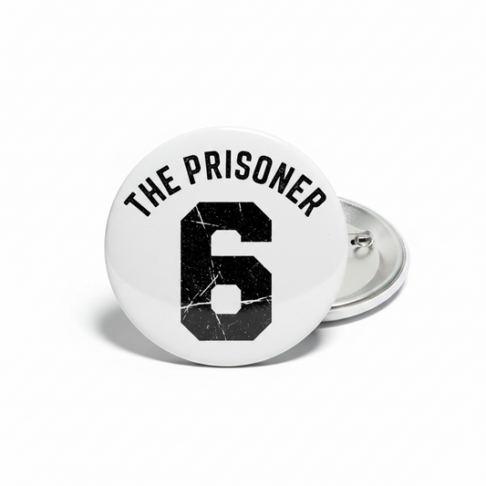 Round pinback button with black “THE PRISONER” text and number 6 emblem