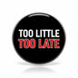 Round black pinback button with chrome edge and “TOO LITTLE TOO LATE” text in white/red