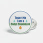 Round pinback button with “Trust Me I am a Camp Counselor” text and trees