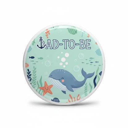 A round button badge featuring a cute underwater theme with a blue whale, orange starfish, and the text 'AD-TO-BE' on a light mint green background.