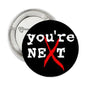 Black pinback button: 'YOU'RE NEXT' with red X