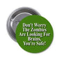 Round green pinback button with white text: zombies looking for brains
